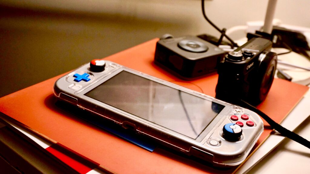A portable gaming console beside a digital camera showcases modern entertainment and technology setup.
